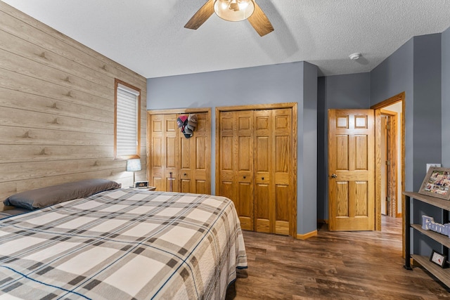 26943 140th St NW, Zimmerman, MN 55398 - bedroom featuring two closets, dark wood-style floors, a textured ceiling, ceiling fan, and wood walls