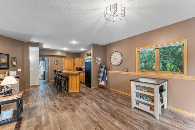 26943 140th St NW, Zimmerman, MN 55398 - kitchen featuring freestanding refrigerator, a kitchen bar, dark wood-style floors, a textured ceiling, and a chandelier