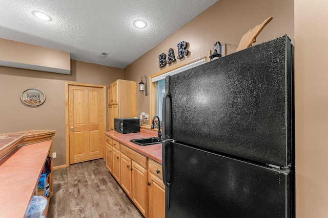 26943 140th St NW, Zimmerman, MN 55398 - kitchen featuring black appliances, light wood-style flooring, a textured ceiling, light countertops, and light brown cabinetry