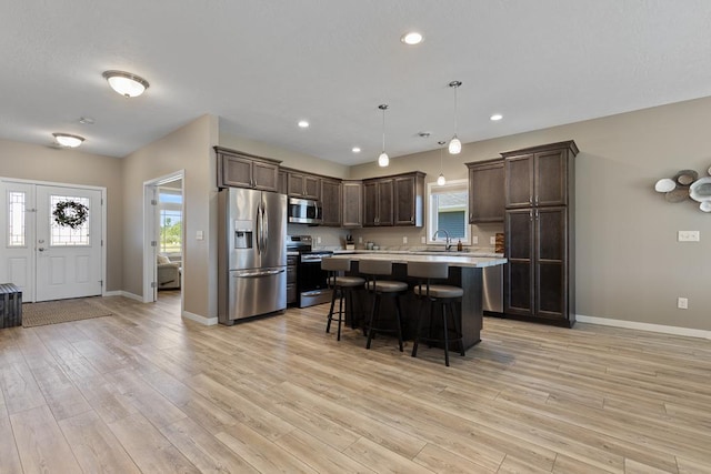 307 Brussels Ct, Marshall, MN 56258 - kitchen featuring stainless steel appliances, dark brown cabinetry, light countertops, a breakfast bar, and light wood-style flooring