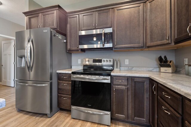 307 Brussels Ct, Marshall, MN 56258 - kitchen featuring stainless steel appliances, dark brown cabinetry, light wood-style floors, and light stone counters