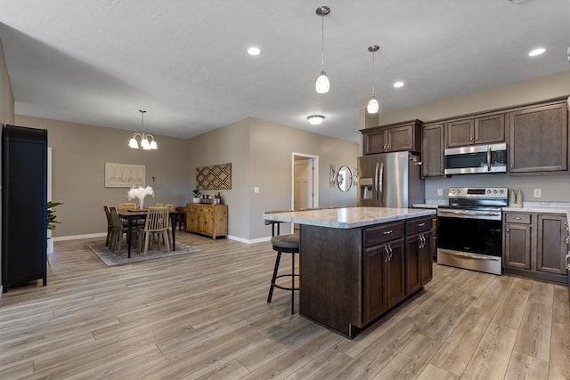 307 Brussels Ct, Marshall, MN 56258 - kitchen with stainless steel appliances, a chandelier, light wood finished floors, dark brown cabinets, and a kitchen breakfast bar