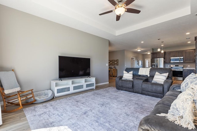 307 Brussels Ct, Marshall, MN 56258 - living room featuring light wood-style floors, a ceiling fan, a tray ceiling, and recessed lighting