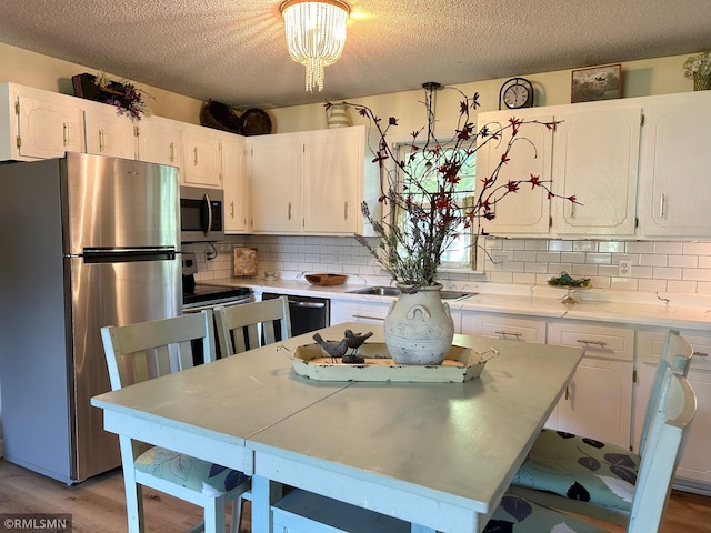 1904 Parkview Rd NE, Alexandria, MN 56308 - kitchen with stainless steel appliances, white cabinetry, a textured ceiling, decorative backsplash, and light wood-style floors