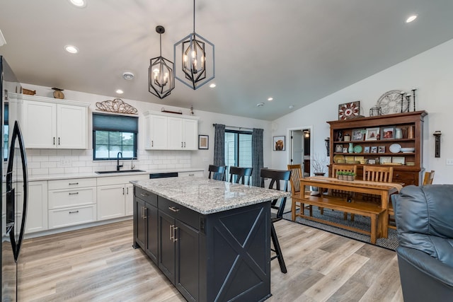 101 Butterfly Ct, Blue Earth, MN 56013 - kitchen with vaulted ceiling, white cabinetry, black fridge, a chandelier, and healthy amount of natural light