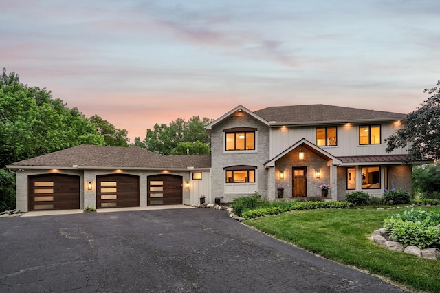 5705 Covington Cir, Minnetonka, MN 55345 - view of front of house with an attached garage, asphalt driveway, a yard, brick siding, and a standing seam roof