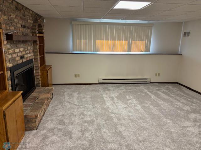 3818 Rivershore Dr, Moorhead, MN 56560 - unfurnished living room with a baseboard radiator, a drop ceiling, carpet flooring, and a fireplace