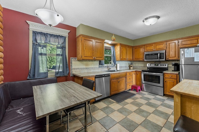 32873 Flanders St NE, Cambridge, MN 55008 - kitchen with stainless steel appliances, light countertops, healthy amount of natural light, a textured ceiling, and brown cabinets