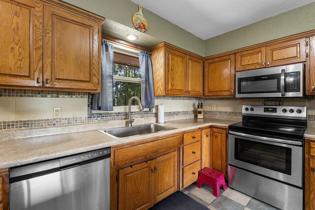 32873 Flanders St NE, Cambridge, MN 55008 - kitchen featuring stainless steel appliances, brown cabinetry, light countertops, and a textured ceiling