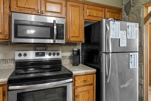 32873 Flanders St NE, Cambridge, MN 55008 - kitchen featuring stainless steel appliances, brown cabinetry, light countertops, and backsplash