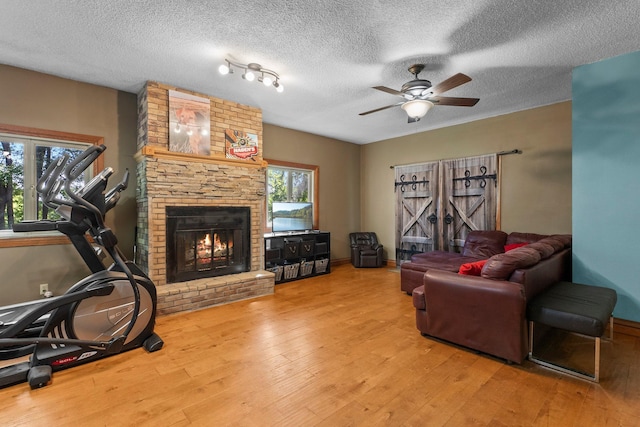 32873 Flanders St NE, Cambridge, MN 55008 - living room featuring wood finished floors, a brick fireplace, ceiling fan, and a textured ceiling