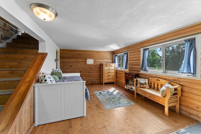 32873 Flanders St NE, Cambridge, MN 55008 - living room with log walls, a textured ceiling, light wood finished floors, and stairs