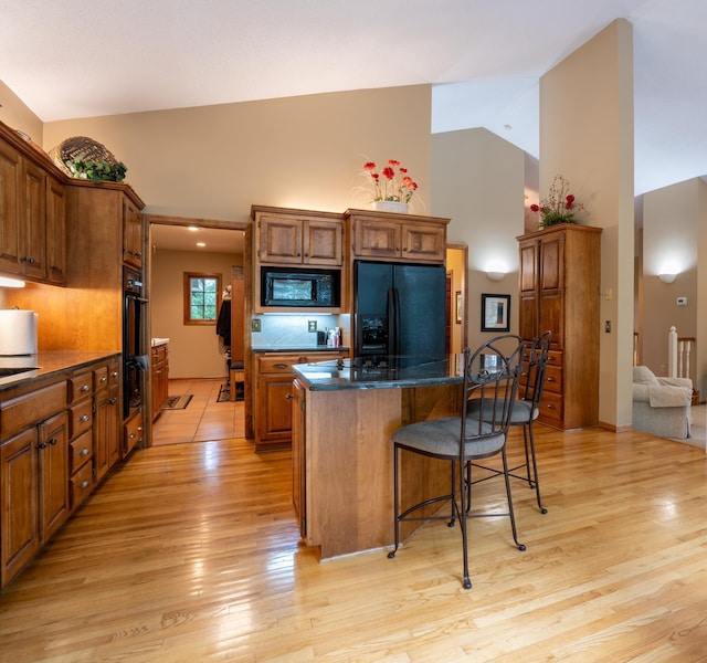 8980 160th Ln NW, Ramsey, MN 55303 - kitchen featuring black appliances, high vaulted ceiling, a kitchen island, a kitchen bar, and light wood finished floors