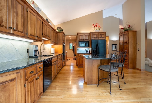 8980 160th Ln NW, Ramsey, MN 55303 - kitchen featuring black appliances, a center island, light wood-type flooring, high vaulted ceiling, and a breakfast bar
