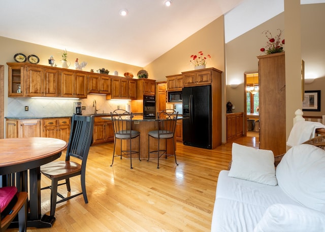 8980 160th Ln NW, Ramsey, MN 55303 - kitchen with black appliances, high vaulted ceiling, dark countertops, brown cabinetry, and decorative backsplash