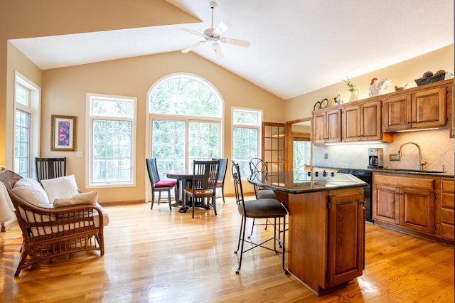 8980 160th Ln NW, Ramsey, MN 55303 - kitchen featuring dark countertops, a breakfast bar area, a ceiling fan, brown cabinetry, and tasteful backsplash