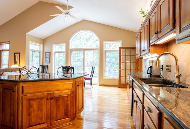 8980 160th Ln NW, Ramsey, MN 55303 - kitchen with light wood finished floors, lofted ceiling, dark stone counters, brown cabinets, and ceiling fan