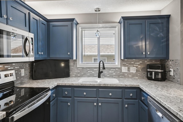 1021 18th Ave SE, Forest Lake, MN 55025 - kitchen featuring stainless steel appliances, blue cabinetry, backsplash, light countertops, and a textured ceiling