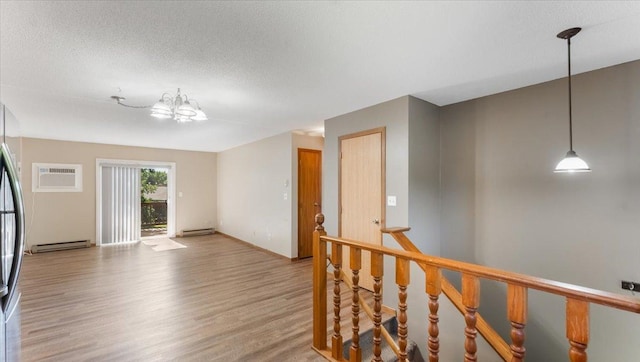 112 9th Ave SE, Saint Joseph, MN 56374 - hall with baseboard heating, an AC wall unit, light wood-style flooring, and a textured ceiling