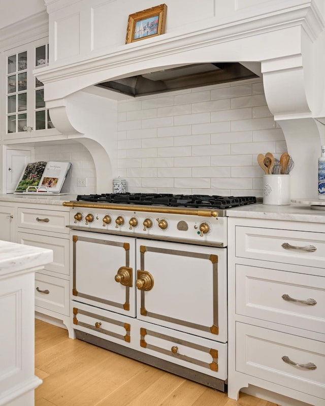 2255 French Creek Cir, Orono, MN 55391 - kitchen with range with two ovens, backsplash, white cabinetry, light wood-style floors, and glass insert cabinets