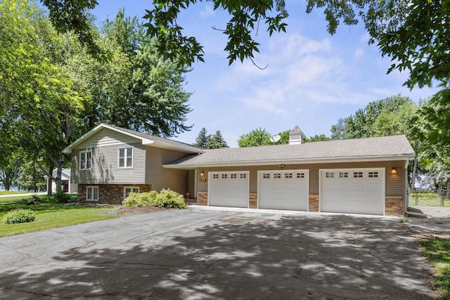 70190 218th St, Dassel, MN 55325 - tri-level home with driveway, stone siding, an attached garage, a front yard, and a chimney