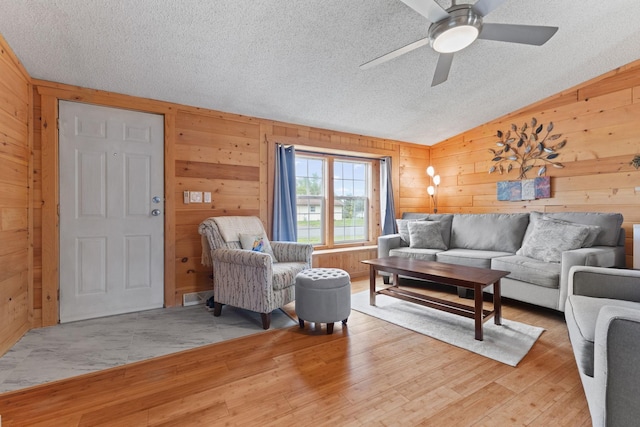 713 Center St, Chetek, WI 54728 - living room featuring wood walls, light wood-type flooring, lofted ceiling, a textured ceiling, and ceiling fan