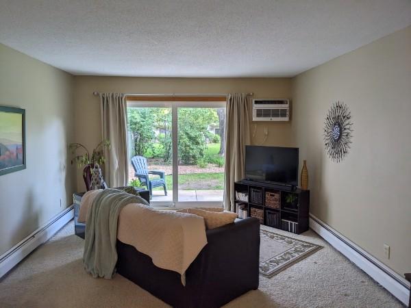 2800 Hillsboro Ave N Unit 113, New Hope, MN 55427 - carpeted living area with a baseboard radiator and a wall mounted air conditioner