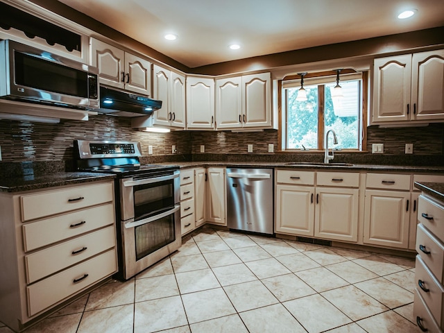 610 25th St SW, Austin, MN 55912 - kitchen featuring stainless steel appliances, under cabinet range hood, decorative backsplash, light tile patterned floors, and recessed lighting