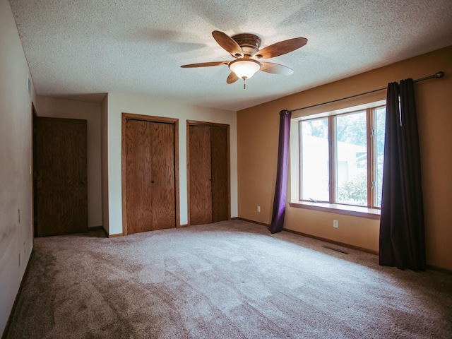 610 25th St SW, Austin, MN 55912 - unfurnished bedroom featuring two closets, carpet flooring, a textured ceiling, and a ceiling fan