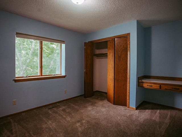 610 25th St SW, Austin, MN 55912 - unfurnished bedroom with a textured ceiling, dark colored carpet, and a closet