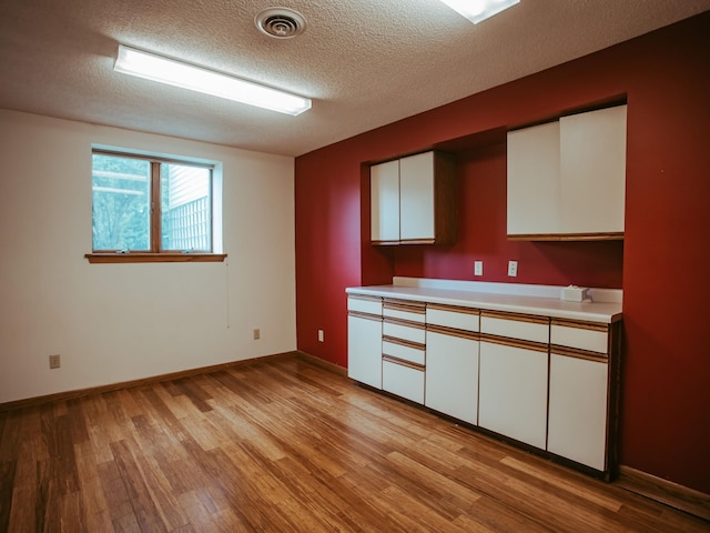 610 25th St SW, Austin, MN 55912 - kitchen featuring white cabinetry, light countertops, light wood-style flooring, and a textured ceiling