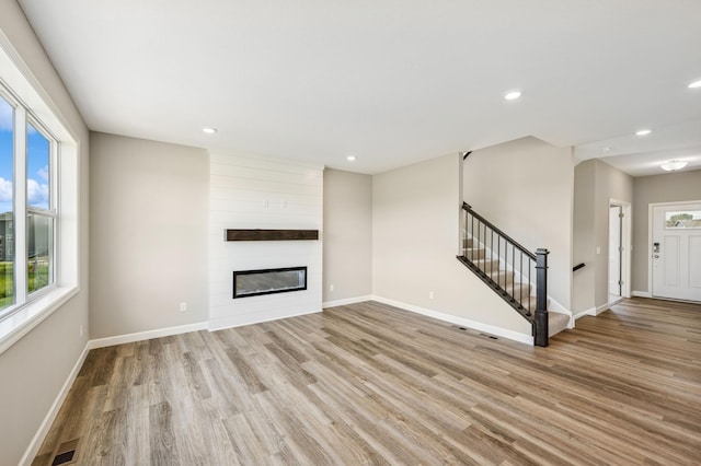 2627 Arbor Dr, Buffalo, MN 55313 - unfurnished living room with stairway, light wood-type flooring, a large fireplace, and recessed lighting