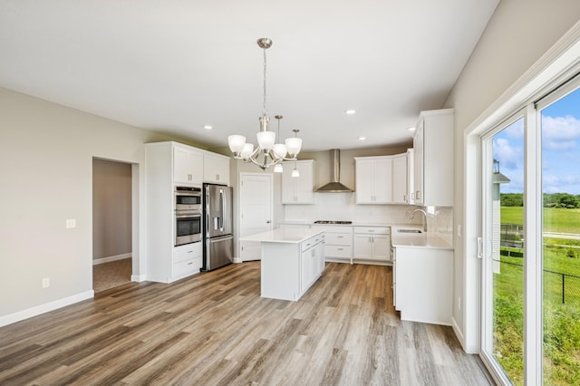 2627 Arbor Dr, Buffalo, MN 55313 - kitchen featuring appliances with stainless steel finishes, wall chimney exhaust hood, a kitchen island, light countertops, and a chandelier