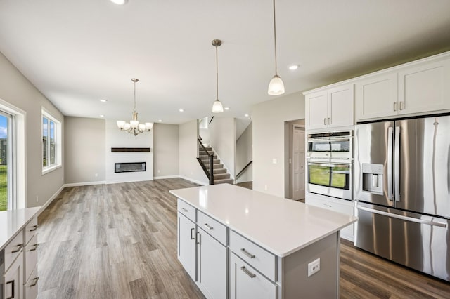 2627 Arbor Dr, Buffalo, MN 55313 - kitchen featuring stainless steel appliances, wood finished floors, a kitchen island, light countertops, and pendant lighting