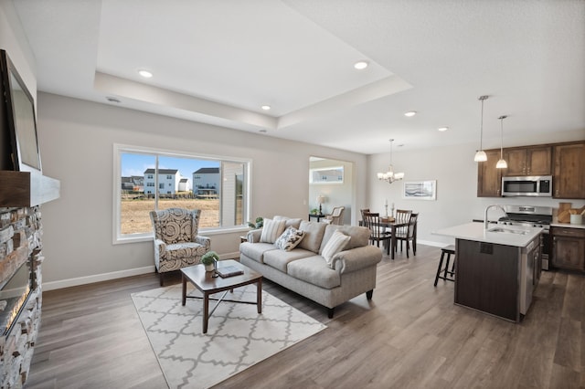 7805 Bridgewater Ct, Greenfield, MN 55373 - living area featuring a raised ceiling, dark wood-style flooring, recessed lighting, a stone fireplace, and a chandelier