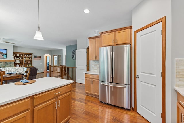 13725 Maxwell Rd, Chisago Lake Twp, MN 55013 - kitchen featuring freestanding refrigerator, arched walkways, light countertops, decorative backsplash, and wood finished floors