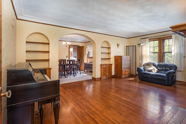 210 1st Ave SW, Glenwood, MN 56334 - living room with built in features, arched walkways, wood finished floors, ornamental molding, and a chandelier