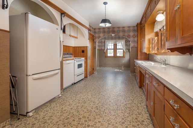 210 1st Ave SW, Glenwood, MN 56334 - kitchen featuring white appliances, brown cabinetry, light countertops, wallpapered walls, and decorative light fixtures