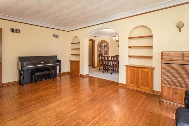 210 1st Ave SW, Glenwood, MN 56334 - living room with built in shelves, arched walkways, light wood-style floors, and crown molding