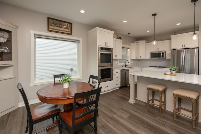 1427 Amco Dr SE, Chatfield, MN 55923 - kitchen with appliances with stainless steel finishes, light countertops, white cabinetry, dark wood-type flooring, and a kitchen bar