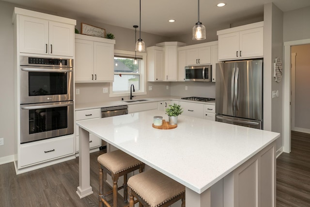 1427 Amco Dr SE, Chatfield, MN 55923 - kitchen featuring appliances with stainless steel finishes, dark wood-style flooring, recessed lighting, white cabinetry, and a kitchen bar