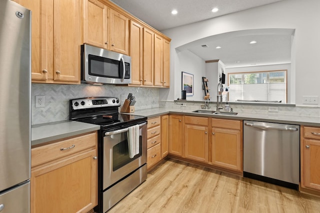 8479 Forestview Ln N, Maple Grove, MN 55369 - kitchen with appliances with stainless steel finishes, light wood-style flooring, decorative backsplash, arched walkways, and recessed lighting