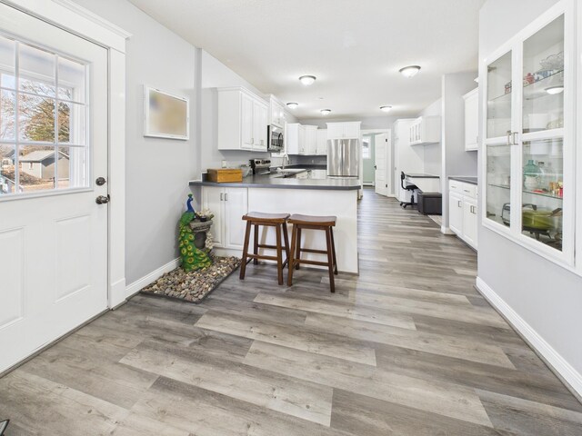 905 3rd Ave SW, Pine City, MN 55063 - kitchen featuring freestanding refrigerator, a peninsula, white cabinetry, light wood-style floors, and a breakfast bar area