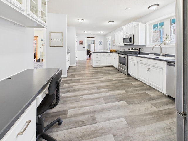 905 3rd Ave SW, Pine City, MN 55063 - kitchen with stainless steel appliances, white cabinetry, a desk, light wood-type flooring, and a peninsula