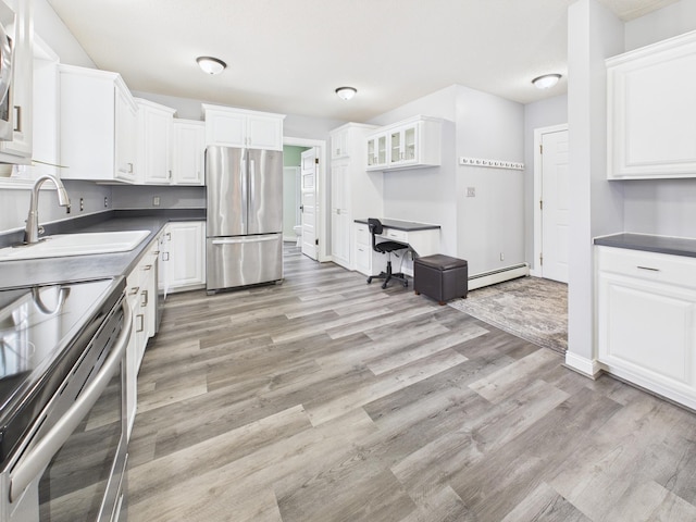 905 3rd Ave SW, Pine City, MN 55063 - kitchen featuring appliances with stainless steel finishes, a baseboard radiator, white cabinets, light wood-style flooring, and glass insert cabinets