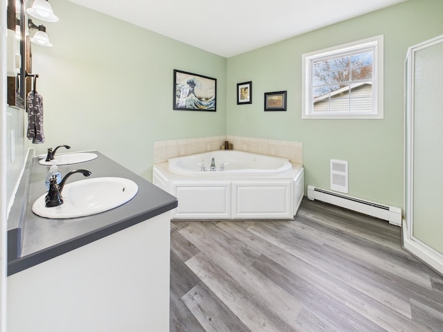 905 3rd Ave SW, Pine City, MN 55063 - full bath featuring a baseboard heating unit, a bath, wood finished floors, a stall shower, and double vanity