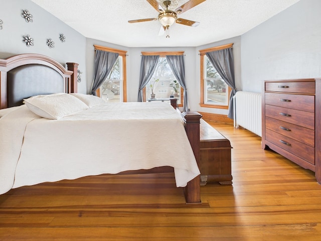 905 3rd Ave SW, Pine City, MN 55063 - bedroom featuring radiator, light wood-style flooring, a textured ceiling, and a ceiling fan