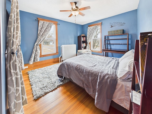 905 3rd Ave SW, Pine City, MN 55063 - bedroom with radiator, wood finished floors, a textured ceiling, and a ceiling fan