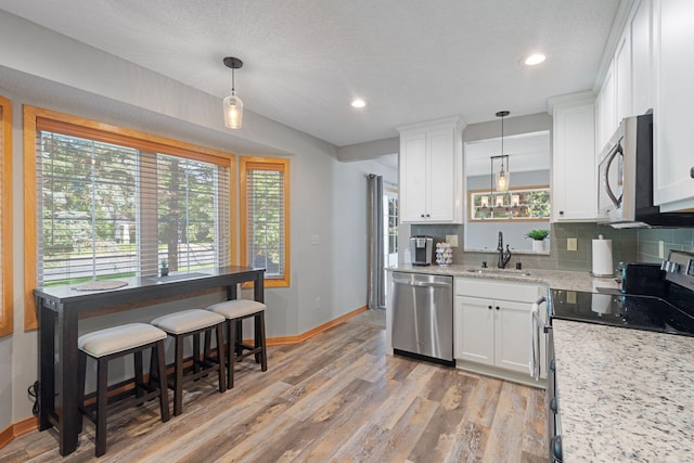 8772 Benson Way Unit 81, Inver Grove Heights, MN 55076 - kitchen featuring stainless steel appliances, light wood finished floors, white cabinetry, decorative backsplash, and recessed lighting