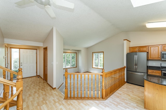 816 Bristol Ln NE, Rochester, MN 55906 - kitchen with appliances with stainless steel finishes, vaulted ceiling, light wood-style floors, dark stone countertops, and a textured ceiling